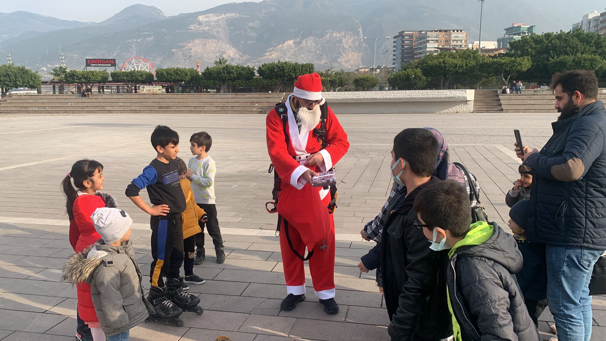 Noel Baba kostümüyle Amanoslar'dan yamaç paraşütüyle atlayıp çocuklara hediye dağıttı