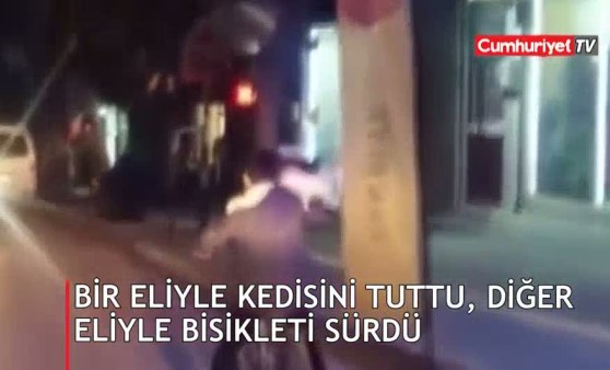 Bir eliyle kedisini tuttu, diğer eliyle bisikleti sürdü